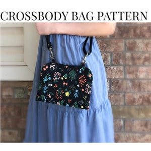 May include: A black crossbody bag with a floral pattern is held against a blue dress. The bag has a black strap and silver hardware. Text on the image reads "CROSSBODY BAG PATTERN" and "BEGINNER FRIENDLY".