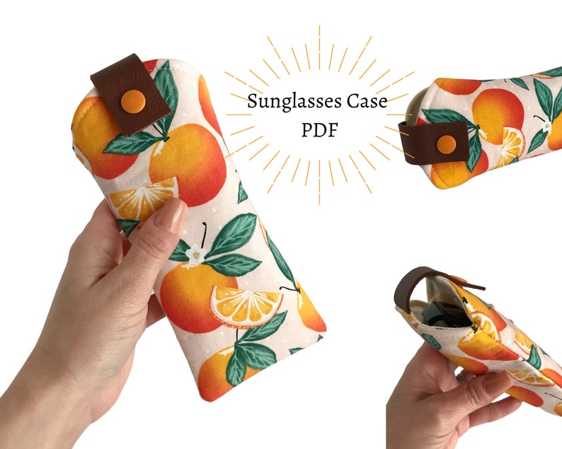 Pode incluir: Um estojo para &oacute;culos de sol de tecido branco com fecho de aba de couro castanho e estampado de citrinos laranja e verde brilhante. O estojo est&aacute; fechado e &eacute; segurado numa m&atilde;o. O texto "Sunglasses Case PDF" &eacute; vis&iacute;vel na imagem.