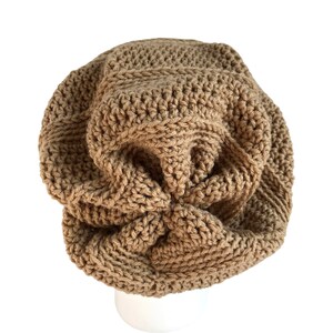 May include: A brown crocheted beanie hat with a unique, textured design. The hat is made with a thick yarn and has a slouchy fit.