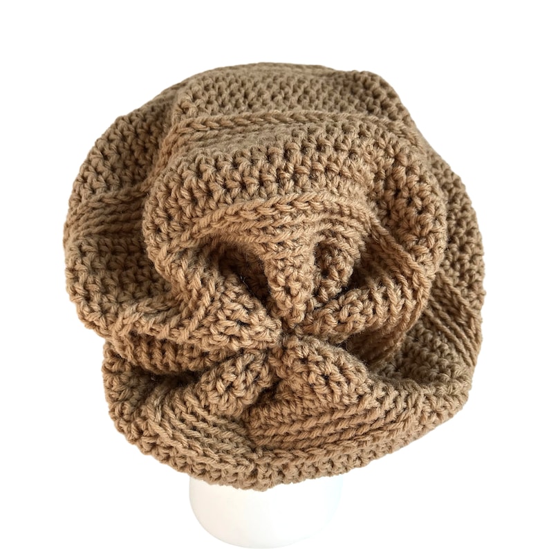 May include: A brown crocheted beanie hat with a unique, textured design. The hat is made with a thick yarn and has a slouchy fit.