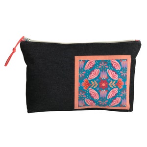 May include: A black denim zippered pouch with a coral-colored pull tab. The pouch features a square patch with a teal background and a floral pattern in pink, orange, and purple.