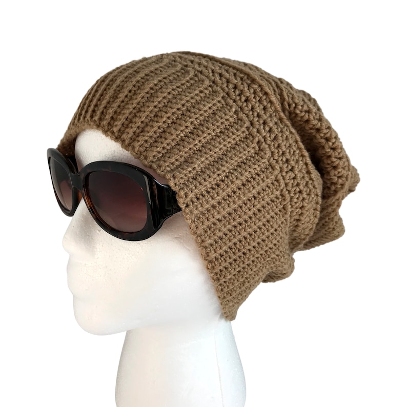 May include: A brown crocheted beanie hat on a white mannequin head. The hat is slouchy and has a ribbed texture.