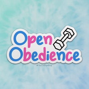 May include: A white sticker with the text "Open Obedience" in blue and pink lettering. A black outline of a dumbbell is to the right of the text. The text "@TheTieDyeDog" is below the text.