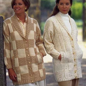 May include: Two women wearing long, button-down knit cardigans. One cardigan is beige and cream checkered, the other is cream-colored with a cable knit design. Both have pockets and are buttoned up. The cardigans are knee-length.