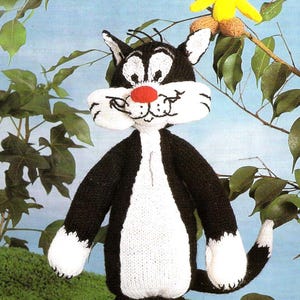 May include: A handmade knitted Sylvester the Cat doll with a red nose and white face, chest, and feet. A yellow Tweety Bird doll is perched on a branch above Sylvester. The background is a light blue sky with green leaves.