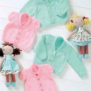Può includere: Diversi cardigan per neonati in maglia, rosa e verde menta, con bottoni. Sono presenti anche due bambole fatte a mano con vestiti di stoffa.
