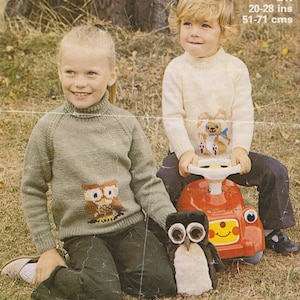 May include: Two children wearing knitted sweaters with animal designs. The girl is wearing a green sweater with an owl design and the boy is wearing a white sweater with a bear design. The boy is sitting on a red toy car with a steering wheel.  DK 20-28 ins 51-71 cms