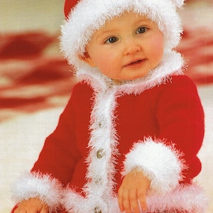 May include: A baby wearing a red knitted Santa suit with white fur trim. The suit has a button closure and the baby is wearing a matching Santa hat.