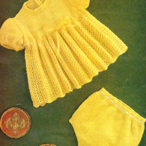 May include: A yellow knitted baby dress with a bow and matching yellow knitted diaper. The dress has a lacy pattern and the diaper has a white trim.