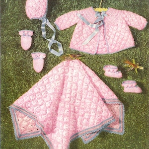 May include: A pink crocheted baby set with a hat, booties, a jacket, and a blanket. The set is trimmed with blue crochet edging.