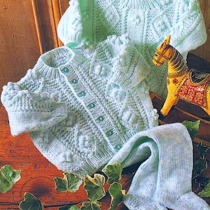 May include: A light blue knitted baby cardigan and matching leggings with a textured pattern. The cardigan has a button closure and the leggings are long.