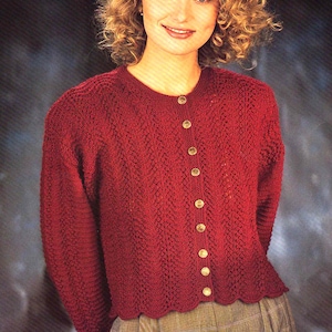 May include: A red knitted cardigan with a scalloped hem and gold buttons. The cardigan is worn over a pair of plaid trousers.