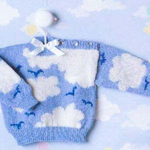 May include: A baby blue knitted sweater with white cloud and bird patterns. The sweater has long sleeves and a round neckline with small buttons. A white ribbon bow is attached to the hanger.