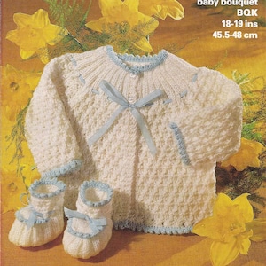 May include: A white knitted baby cardigan with blue trim and a blue ribbon tied at the neckline. The cardigan is paired with matching white knitted booties with blue trim and blue ribbons. The image includes the text "baby bouquet BQK 18-19 ins 45.5-48 cm".