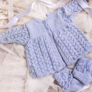 Puede incluir: Un cárdigan de bebé de punto azul claro y botines a juego con un delicado patrón de encaje.