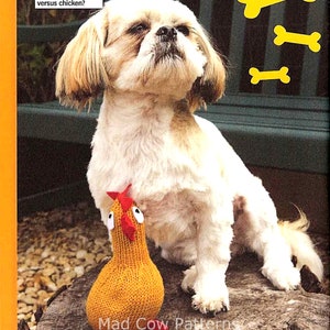 May include: A white dog with brown fur on its head and ears sits on a wooden stump. The dog is looking up at the camera. A knitted orange chicken toy with red accents sits in front of the dog. The text "Ready for battle - who will win in dog versus chicken?" is in the top left corner of the image. Three yellow bone shapes are in the top right corner of the image.