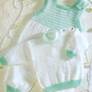 Puede incluir: Un jersey de punto blanco para bebé con ribetes verdes y un pelele sin mangas a juego de rayas blancas y verdes. El pelele tiene botones en los hombros.
