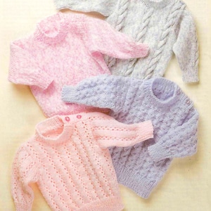 May include: Four knitted baby sweaters in different colors and patterns. The sweaters are pink, light blue, and purple. The sweaters are all made with a cable stitch pattern.