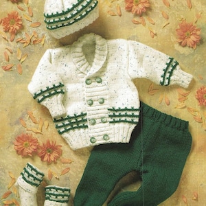 May include: A knitted baby outfit in white and green. The set includes a cardigan, trousers, hat, and booties. The cardigan has a white background with green trim and buttons. The trousers are solid green. The hat has a white pom-pom on top.
