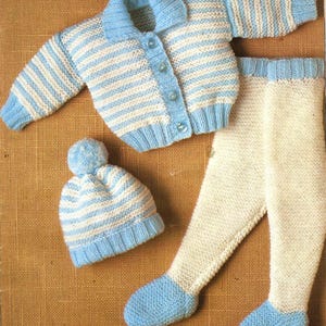 Puede incluir: Un conjunto de bebé tejido en rayas blancas y azul claro. El conjunto incluye una rebeca con botones, un gorro con pompón y un par de leggings. El conjunto está hecho de hilo suave, perfecto para un recién nacido.