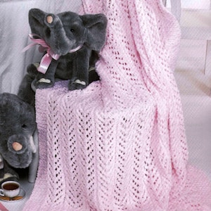 May include: A pink crocheted baby blanket with a delicate open stitch pattern. The blanket is draped over a chair with a gray stuffed elephant toy sitting on it.