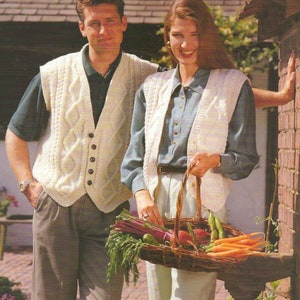 Könnte beinhalten: Ein Paar trägt weiße, gestrickte, ärmellose Pullover mit Knöpfen. Der Mann trägt eine braune Hose und die Frau hält einen Korb mit Gemüse.