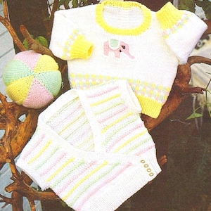 Puede incluir: Dos jerséis de punto para bebé, uno con una aplicación de elefante rosa y el otro con rayas amarillas y rosas. También se incluye una pelota de punto amarilla, rosa y verde.