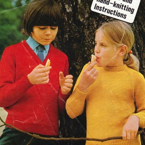 Pode incluir: Duas crianças, uma vestindo um suéter vermelho e a outra vestindo um suéter amarelo, estão em pé na frente de uma árvore. A criança com o suéter vermelho está segurando um pedaço de pão. A criança com o suéter amarelo está comendo um pedaço de pão. O texto "Machine and Hand-knitting Instructions" é visível na imagem.