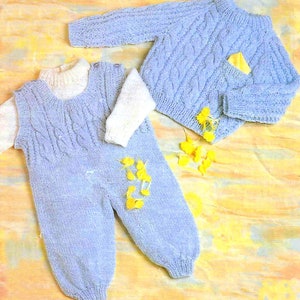 Könnte beinhalten: Ein gestricktes Baby-Outfit in hellblau. Das Outfit besteht aus einem langärmeligen Pullover und einer Latzhose mit einem weißen Rollkragen.