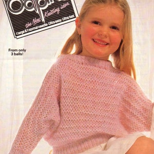 May include: A pink knitted sweater with a loose fit and a textured stitch pattern. The sweater is made with a soft yarn and has a relaxed, comfortable look. The text "Odpins the New Knitting idea 1 large & 1 normal needle Ultra easy Ultra fast From only 3 balls!" is printed on a black and white label.