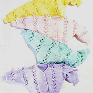 May include: Four pastel-coloured knitted baby cardigans. The cardigans are yellow, pink, mint green, and lavender. Each has a button closure and decorative ribbon ties on the sleeves. The knit design features openwork patterns.