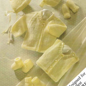 May include: A set of knitted baby clothes in a pale yellow color, including a cardigan, a vest, a hat, booties, and mittens. The text "Specially designed for the smallest PREMATURE BABIES." is printed on the image.
