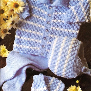 Puede incluir: Un conjunto de punto azul bebé compuesto por un cárdigan, un gorro, botines y polainas con rayas blancas. El conjunto está hecho con un punto texturizado y tiene cierre de botones. El cárdigan está etiquetado como "Little Angel DK 41-56 cm (16-22 pulgadas)".