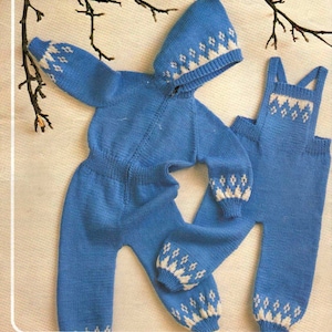 May include: A blue knitted baby outfit with a white geometric pattern. The outfit includes a hooded jumpsuit and matching dungarees.