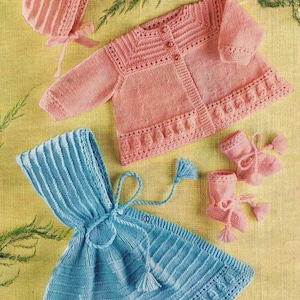 May include: A selection of hand-knitted baby clothes in pastel shades. The set features a pink bonnet with a ribbon, a pink cardigan with button fastenings, a blue hooded dress with tassels, and pink booties.