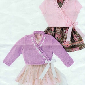 May include: Two knitted baby cardigans in pink and purple with white ribbon ties. The cardigans are styled with matching skirts.