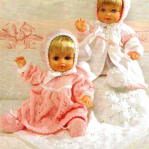 May include: Two knitted doll outfits in pink and white. The outfits include dresses, hats, and booties. The dolls are not included.