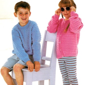 Puede incluir: Dos niños con suéteres de punto. El niño lleva un suéter azul claro y está sentado en una silla blanca. La niña lleva un cárdigan rosa y pantalones a rayas. Ella sostiene gafas de sol en sus manos.