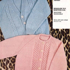 Könnte beinhalten: Zwei gestrickte Baby-Cardigans, einer hellblau und einer rosa, mit Knöpfen. Die Cardigans liegen auf einem Leopardenmusterstoff. Der Text auf dem weißen Etikett lautet "1115 Knit into to fashion BEAULON D.K. BABYKIN D.K. MACHINE WASHABLE 18 to 24 inch chest (46 to 61 cm)"