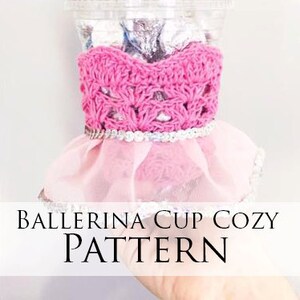 May include: Pink crocheted ballerina cup cozy with a tulle skirt and a silver trim. The cozy is designed to fit a standard-sized cup. "Ballerina Cup Cozy Pattern" is written in black text on a white background.