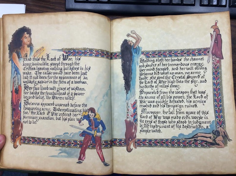 May include: An illustrated book page with a hand-painted image of a woman holding a sword. The text on the page reads "And thus the Lord of War..." and "Holding aloft her hands..."
