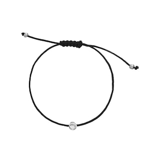 May include: A simple black string bracelet with a small, clear crystal charm.