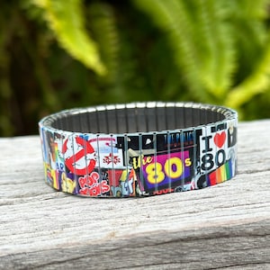 May include: A silver expandable bracelet with a colorful collage of 1980s pop culture icons, including Ghostbusters, the words "the 80s", and "I Love the 80s".