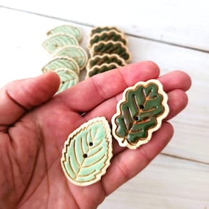 May include: A set of ceramic buttons featuring leaf designs. The buttons are green and white with a textured finish.