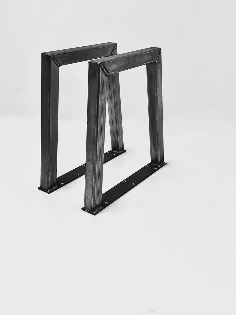 May include: Two black metal table legs with a rectangular base and a triangular frame.