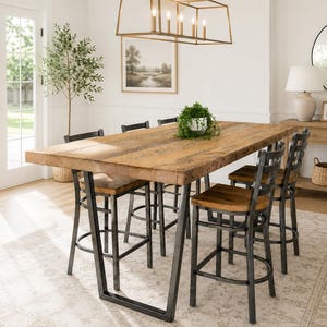 May include: A rustic dining table with a thick, reclaimed wood top and black metal legs. Six matching bar stools with wooden seats and metal frames surround the table. A small potted plant sits in the center of the table, creating a warm, inviting dining space.