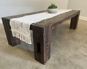 May include: A dark stained wooden coffee table with a white crocheted table runner and a small potted succulent plant in a white planter.