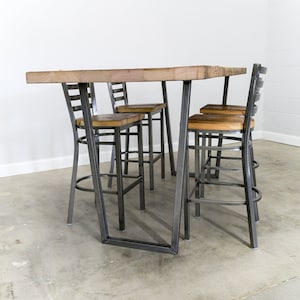 May include: A wooden table with a metal frame and four metal chairs. The table and chairs are in a light wood finish and the metal is a dark gray color.
