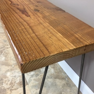 K&ouml;nnte beinhalten: Eine Holzbank mit nat&uuml;rlicher Holzoptik und Haarnadelbeinen. Die Bank ist aus recyceltem Holz gefertigt und hat einen rustikalen Look.
