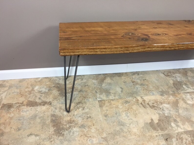 K&ouml;nnte beinhalten: Eine Holzbank mit nat&uuml;rlicher Holzoptik und Haarnadelbeinen. Die Bank ist aus recyceltem Holz gefertigt und hat einen rustikalen Look.